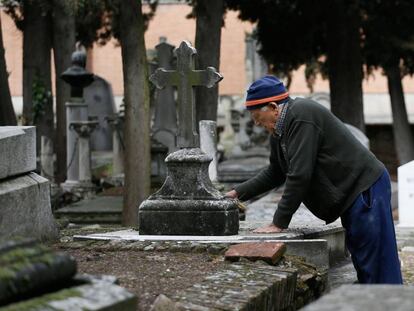 Urbano, de 78 años, limpia una lápida en el cementerio civil de La Almudena, en Madrid.