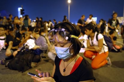 Una estudiante sigue las noticias en una protesta que rodea la sede del Gobierno. 