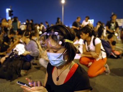 Una estudiante sigue las noticias en una protesta que rodea la sede del Gobierno. 