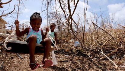 Tiquania Lewis, de dos años y su hermana Tiquanisha, de cinco, juegan cerca de unos árboles derribados por el huracán Irma en la isla de Anguilla, en el Caribe, en septiembre de 2017.  