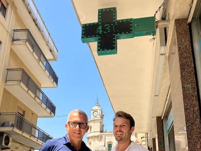 De izquierda a derecha, Elio Morale y Biagio Cantone, debajo del termómetro de su farmacia en Floridia, Sicilia, el municipio donde en 2021 se registró el récord europeo de calor, 48,8 grados (medido en una estación meteorológica).