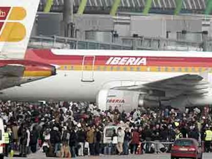 Cientos de pasajeros aguardan en las pistas del aeropuerto a ser evacuados en autobuses hacia la terminal 2.
