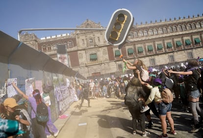 Manifestantes golpean una luz de semáforo en el Zócalo de la Ciudad de México, frente a Palacio Nacional.