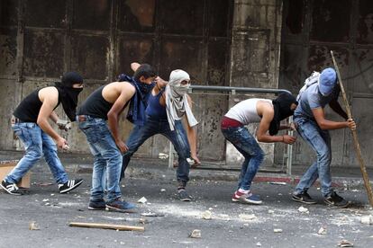 Un grupo de palestinos se cubre durante los choques con las fuerzas de seguridad israelíes.