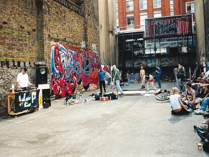 Un DJ pincha en el aparcamiento mientras un grupo de jóvenes baila break dance mientras otros pintan graffitis.