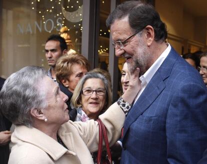 El presidente del Gobierno y candidato a la reelección por el PP, Mariano Rajoy, saluda a una mujer durante un recorrido por las calles de Vigo, dentro de la campaña para las elecciones generales del 20D.