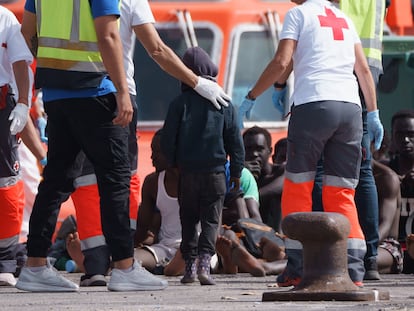 Dos miembros de Cruz Roja acompañan a un niño llegado en un cayuco a Tenerife en abril.