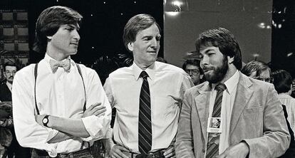 Steve Jobs, con los tirantes y la pajarita que lucía en 1984 en una presentación de novedades de Mac (junto a John Sculley y Steve Wozniak).