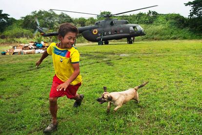 Luis Napa y su perro &quot;Pelusa&quot; juegan en el estadio de Pedernales, Ecuador, mientras un helic&oacute;ptero del Ej&eacute;rcito deja ayuda humanitaria.