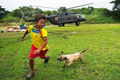 Luis Napa y su perro &quot;Pelusa&quot; juegan en el estadio de Pedernales, Ecuador, mientras un helic&oacute;ptero del Ej&eacute;rcito deja ayuda humanitaria.