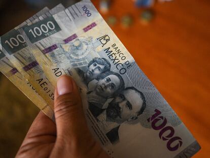 Un hombre sostiene tres mil pesos mexicanos.