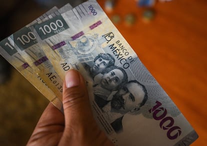 Un hombre sostiene tres mil pesos mexicanos.