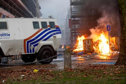 Un vehículo de la policía belga pasa cerca de una hoguera encendida por los manifestantes, este domingo en Bruselas.