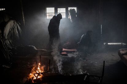 Grupos de refugiados se calientan con hogueras en uno de los almacenes del complejo ferroviario abandonado en el centro de Belgrado (Serbia).