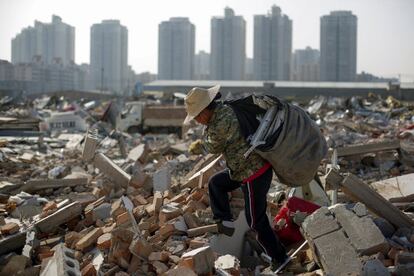 Migrant worker Wang Jun carries scrap material she collected from debris of demolished buildings at the outskirts of Beijing, China October 1, 2017. Picture taken October 1, 2017. REUTERS/Thomas Peter