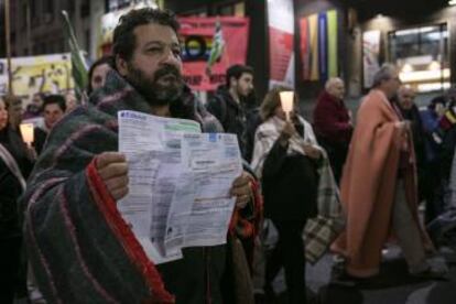 Un hombre muestra las boletas de agua y energía durante la movilización.