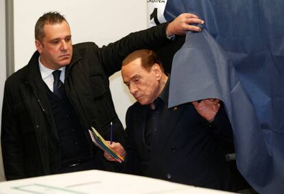 Silvio Berlusconi abandona una cabina electoral antes de votar en Milán.