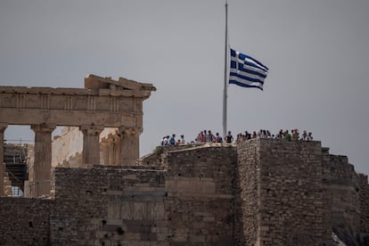 La bandera griega ondea a media asta junto al Partenón mientras los turistas visitan la antigua Acrópolis de Atenas, este jueves.