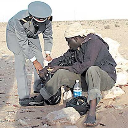 Un gendarmes ayuda a Soldi, inmigrante de Gambia, a levantarse.