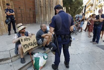 Un agente, junto a varios indignados ayer en la plaza del Ayuntamiento de Valencia.