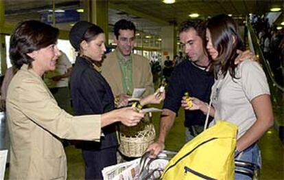 Pilar Cáceres y Fernando Moraleda, entregan una botellita de aceite a una pareja en el aeropuerto de Barajas.