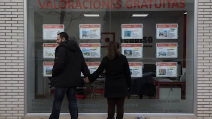 Dos jóvenes miran un escaparate con anuncios de pisos en el Ensanche de Vallecas (Madrid). 