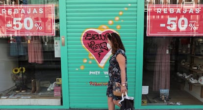 MADRID, 20/07/2020.- Una viandante, protegida con mascarilla, pasa por delante de una tienda de ropa