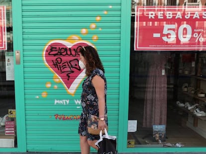 MADRID, 20/07/2020.- Una viandante, protegida con mascarilla, pasa por delante de una tienda de ropa