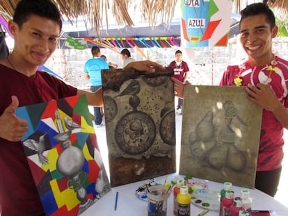 Waldo Flores (i) y otro joven muestran sus pinturas.