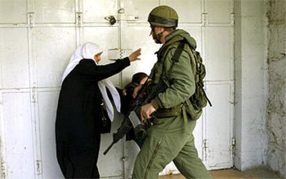 Una mujer palestina trata de pasar frente a un soldado israelí en Hebrón.