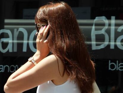 Una mujer habla por tel&eacute;fono en una calle de Madrid.