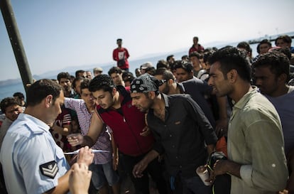 Un grupo de inmigrantes se agolpa ante un agente de policía en la isla griega de Kos para intentar conseguir la documentación para entrar en Europa.