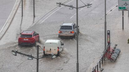 Varios vehículos circulan por una calle inundada en Zaragoza, este jueves. 