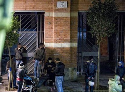 Viandantes y jóvenes charlan frente a la entrada del edificio donde está el piso <i>ocupado</i>.