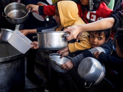 Unos niños palestinos aguardan con cacerolas el reparto de comida de una organización humanitaria en Rafah, en el sur de Gaza, el 5 de marzo.