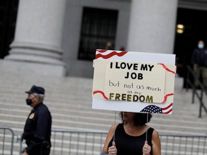 Una mujer sostiene un cartel que dice que ama su trabajo, pero no tanto como su libertad, en una protesta contra las vacunas obligatorias de la ciudad de Nueva York