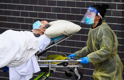 Un sanitario traslada a un enfermo de coronavirus a un centro hospitalario en Melbourne (Australia). El país registró este lunes 549 nuevos casos en 24 horas, un récord desde el inicio de la pandemia.