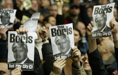 Fanáticos del Manchester United provocan a un grupo de personas del Liverpool con los carteles de Boris Johnson, durante un partido de fútbol en el estadio Anfiel, el 15 de enero de 2005. En octubre del año anterior, Johnson había visitado Liverpool para realizar una disculpa formal después de que la revista 'The Spectator' publicara un artículo que describía a la ciudad como "enganchada a la pena" desde el asesinato del rehén Kenneth Bigley.