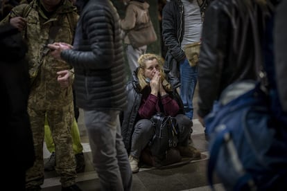 Una mujer llora mientras espera en la estación de tren de Kiev.