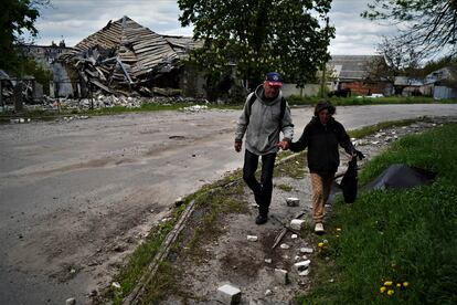 Una pareja camina delante de una vivienda bombardeada en Kupiansk.