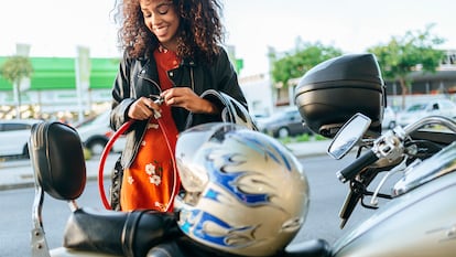 Una chica poniéndole el candado a su moto.
