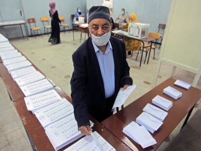 Un votante recoge las papeletas de las listas de candidatos, este sábado en un colegio electoral de Argel.