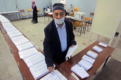 Un votante recoge las papeletas de las listas de candidatos, este sábado en un colegio electoral de Argel.