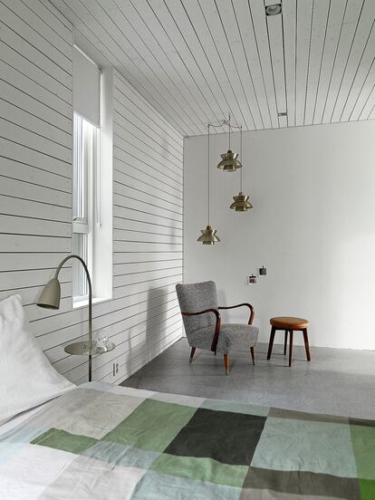Madera tratada. El dormitorio está forrado de madera blanca para combinar calidez y luminosidad. La cama es de E15; las lámparas, de Lindsey Adelman, y la butaca danesa, de Jakob Kjaer.