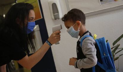 Una professora pren la temperatura a un nen a l'escola Mare de Déu de Monserrat de Terrassa.