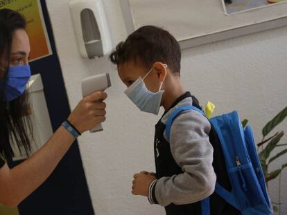 Una professora pren la temperatura a un nen a l'escola Mare de Déu de Monserrat de Terrassa.