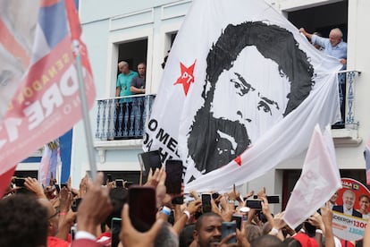 El candidato presidencial Lula junto a una enorme bandera con su imagen de una ficha policial de los ochenta, este domingo en un mitin en Río de Janeiro.