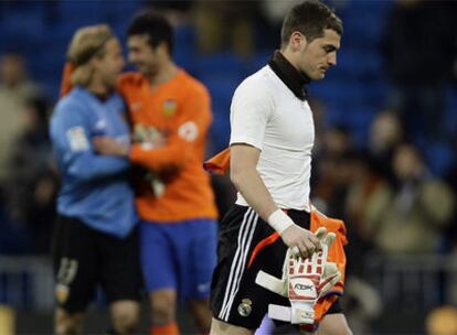 Casillas se retira cabizbajo al final del partido mientras Hildebrand y Albiol, al fondo, celebran el triunfo del Valencia en el Bernabéu.