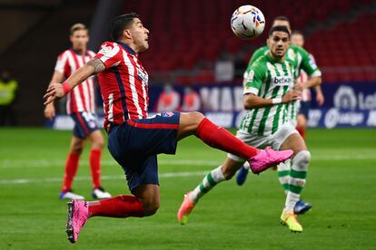 Luis Suárez trata de controlar el balón ante el central del Betis Marc Bartra. / (Photo by GABRIEL BOUYS / AFP)