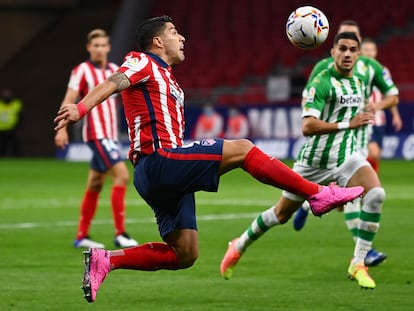 Luis Suárez trata de controlar el balón ante el central del Betis Marc Bartra. / (Photo by GABRIEL BOUYS / AFP)